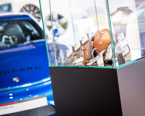 Blue Porsche behind a glass cabinet of Jewellery