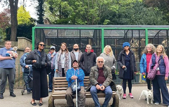 Group of people stood and sitting with bird cages behind them