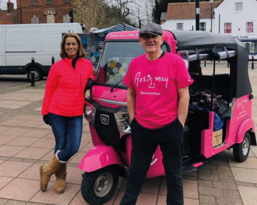 Two people stood next to a pink Tuk-Tuk